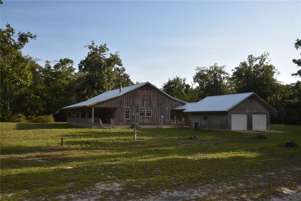 A rustic wooden house with a metal roof, wraparound porch, and attached two-car garage — 5351 SW COUNTY ROAD 347, CEDAR KEY, FL