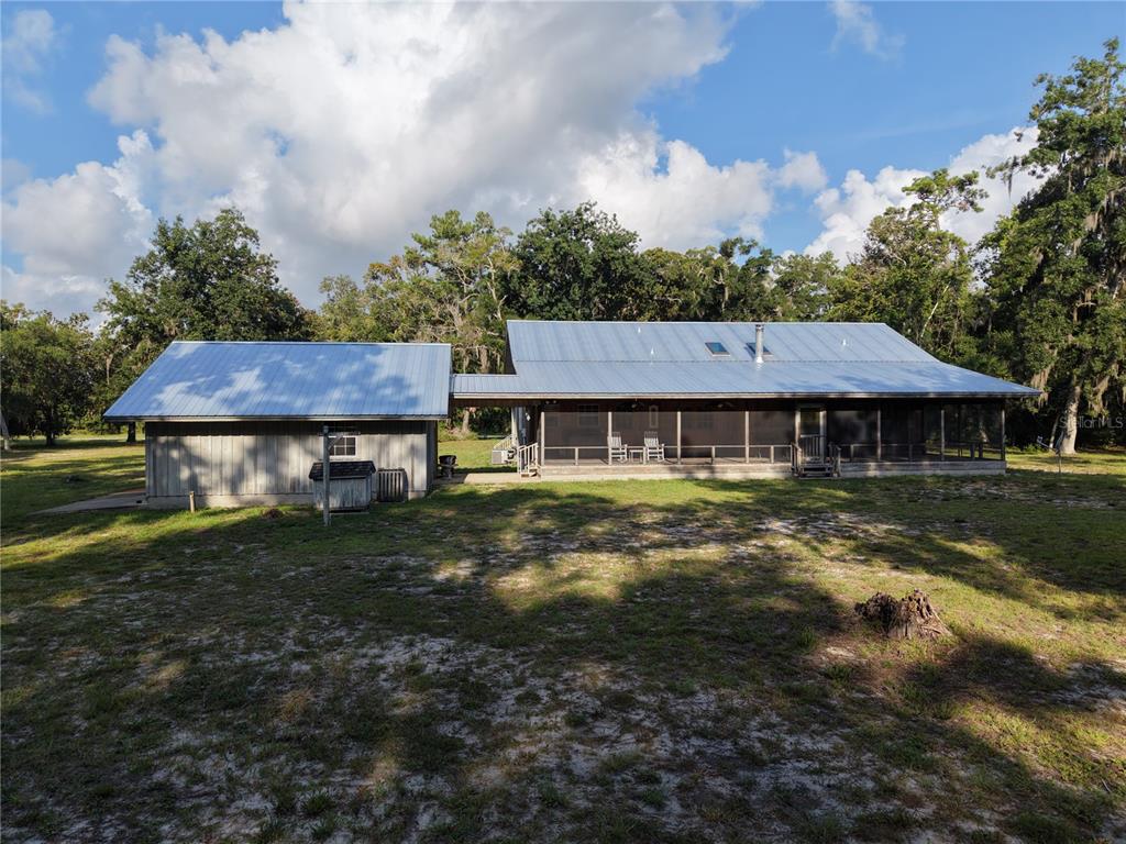 A metal-roofed house with a screened porch is connected to a detached garage by a walkway — 5351 SW COUNTY ROAD 347, CEDAR KEY, FL