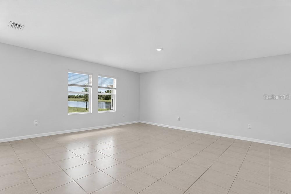 An open-concept living room and kitchen with white cabinetry, a sectional sofa, and teal accents — 13840 SHELLMORE AVENUE, PALMETTO, FL