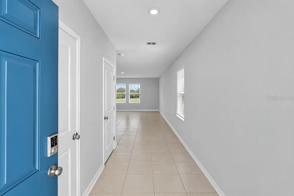 A living room features a beige sofa, teal armchair, gold shelving, and a large window — 13840 SHELLMORE AVENUE, PALMETTO, FL