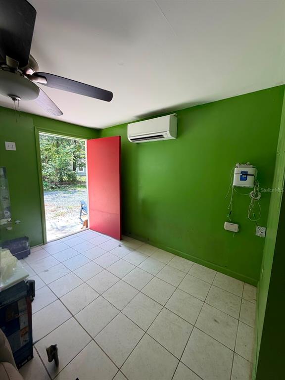 A room with green walls, white tile floors, a ceiling fan, and a wall-mounted air conditioner — 427 POLK AVENUE, ORANGE PARK, FL