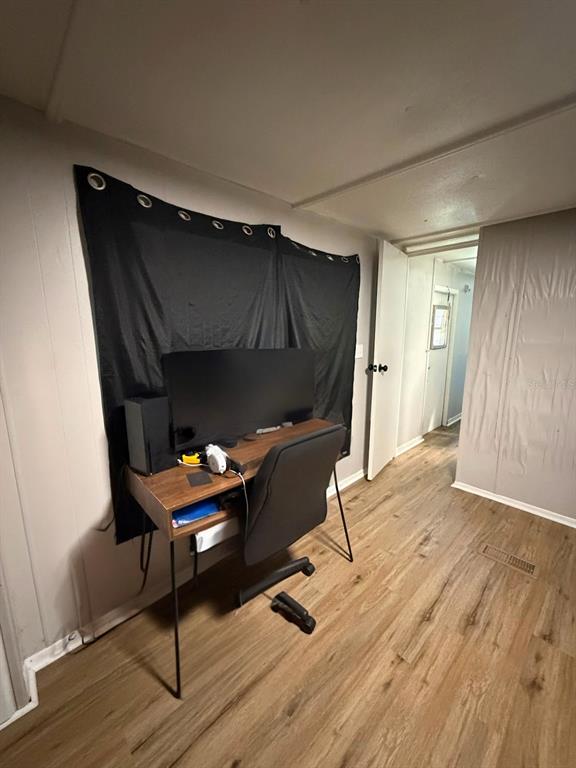 A room with wood-look flooring features a desk with a computer monitor against a curtained wall — 427 POLK AVENUE, ORANGE PARK, FL