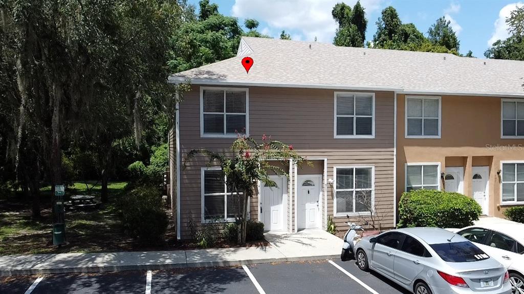 A two-story tan siding townhouse exterior features a pet waste station and a wooded area — 4415 SW 34TH ST UNIT 410, GAINESVILLE, FL