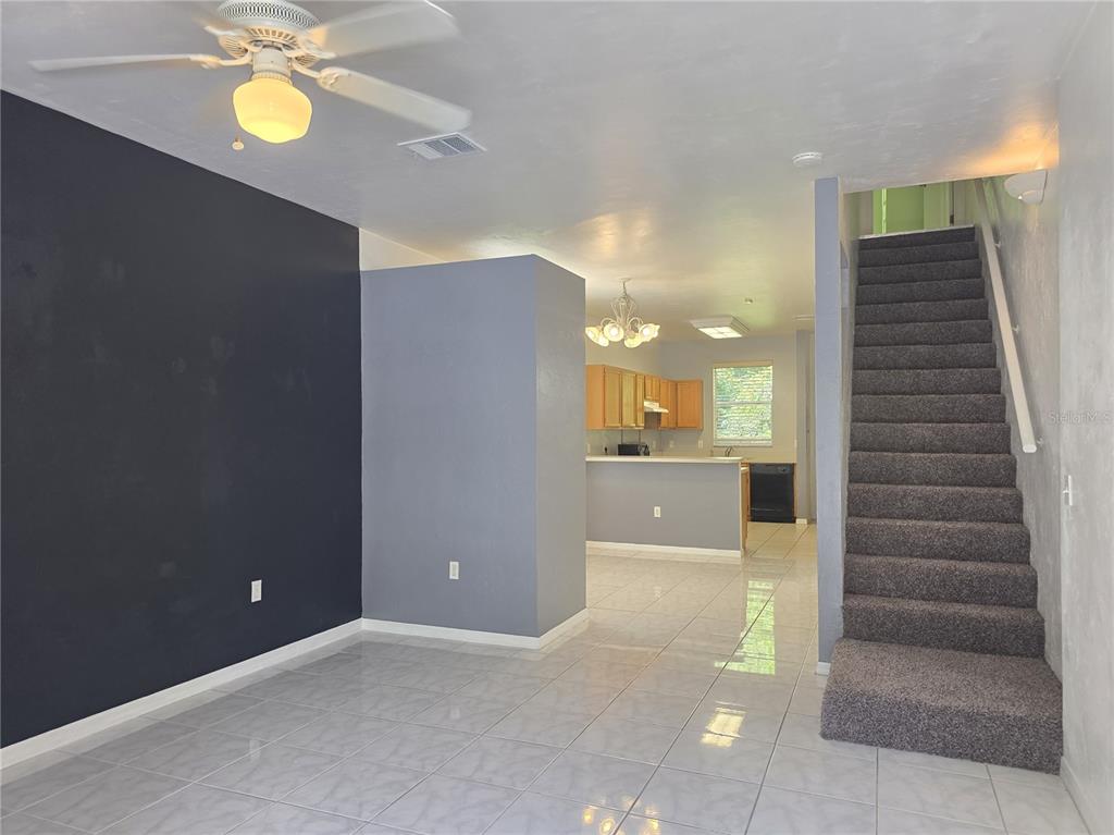 A living room with a gray sectional sofa, tiled floors, and stairs leading to an upper level — 4415 SW 34TH ST UNIT 410, GAINESVILLE, FL