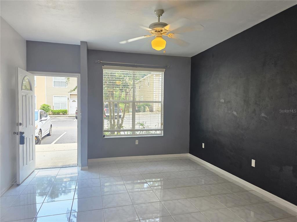 A living room with a dining table, sofa, and an open door leading outside — 4415 SW 34TH ST UNIT 410, GAINESVILLE, FL