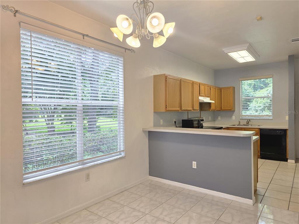 A dining area with a round table and wicker chairs sits adjacent to a kitchen — 4415 SW 34TH ST UNIT 410, GAINESVILLE, FL