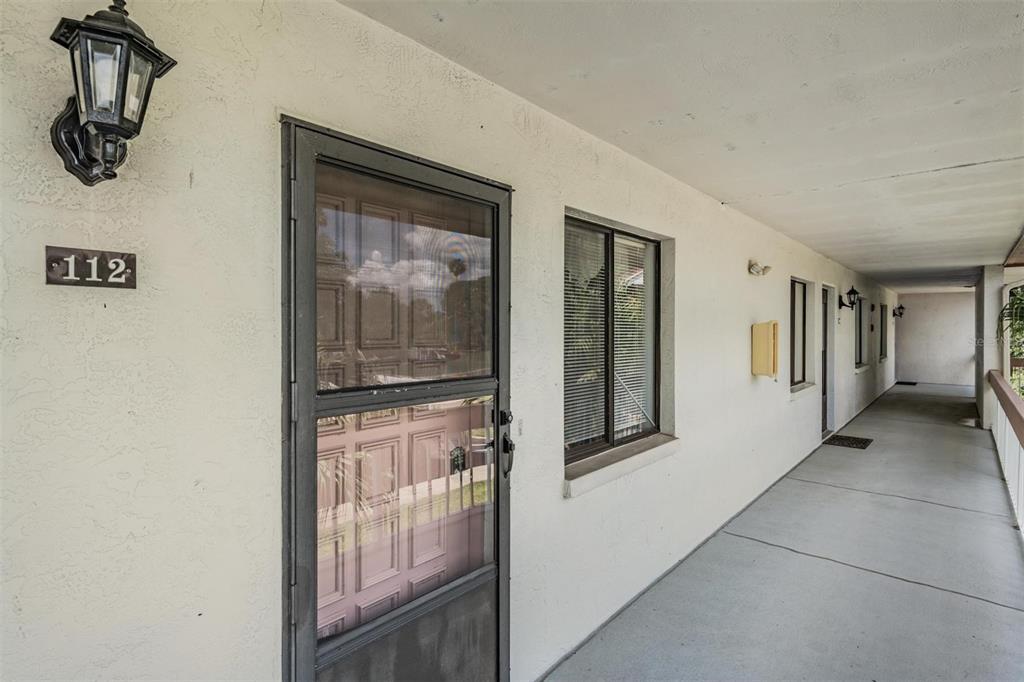 An exterior view of a building corridor showing a numbered apartment door and window — 112 LAKEVIEW PLACE UNIT 12, OLDSMAR, FL