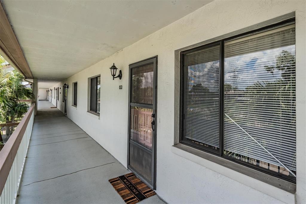 An exterior walkway leads to a front door with a screen and a large window — 112 LAKEVIEW PLACE UNIT 12, OLDSMAR, FL