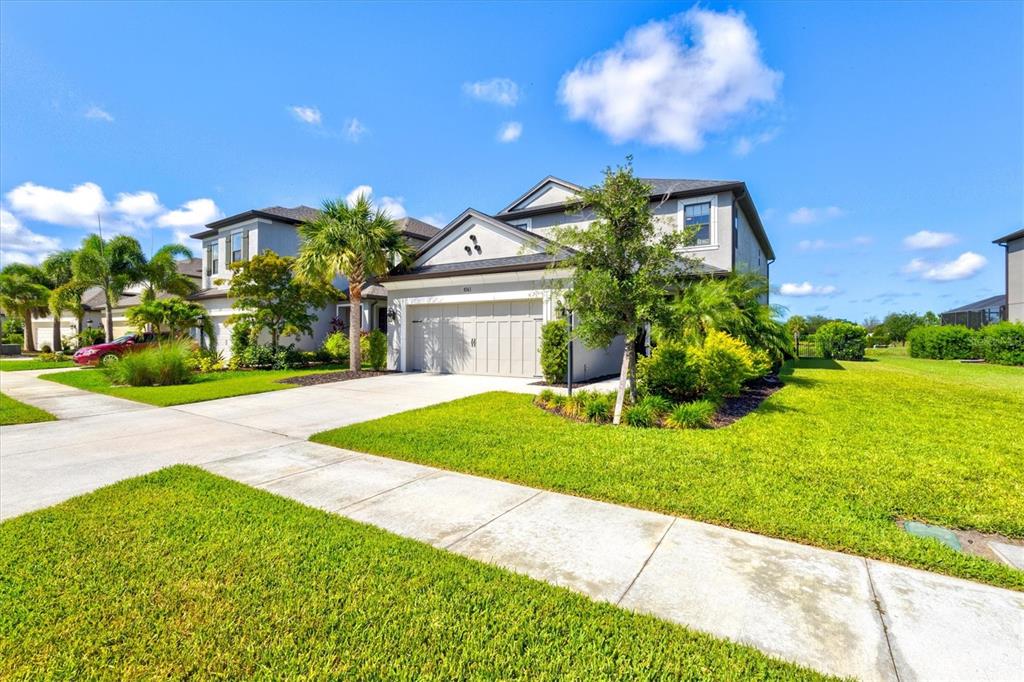 A two-story suburban house with a gray exterior, a two-car garage, and a manicured lawn — 8363 VELDA TRAIL, SARASOTA, FL