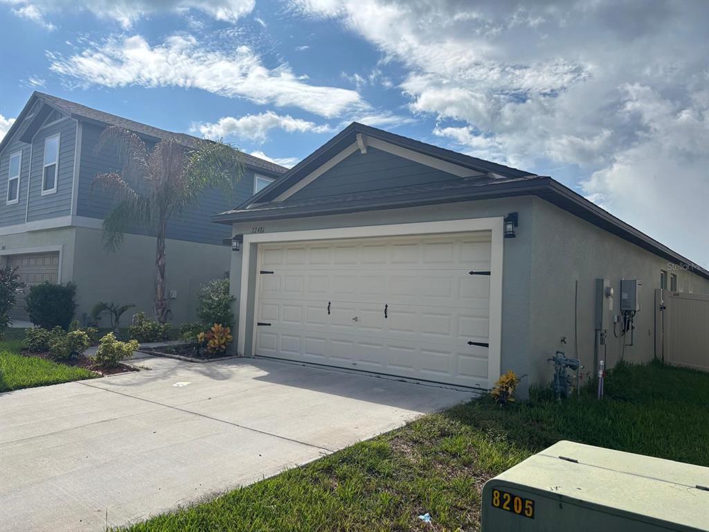 A beige one-story house with a two-car garage and a gray gable roof — 22481 STORYBOOK CABIN WAY, LAND O LAKES, FL