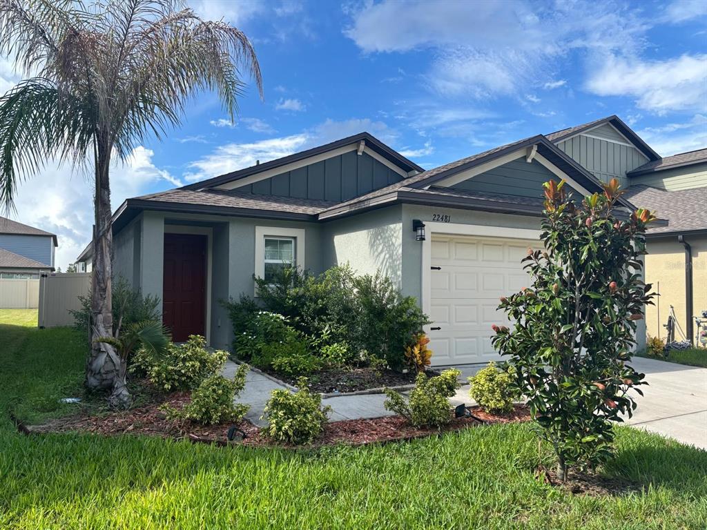 A single-story house with a beige stucco exterior, a red front door, and a garage — 22481 STORYBOOK CABIN WAY, LAND O LAKES, FL
