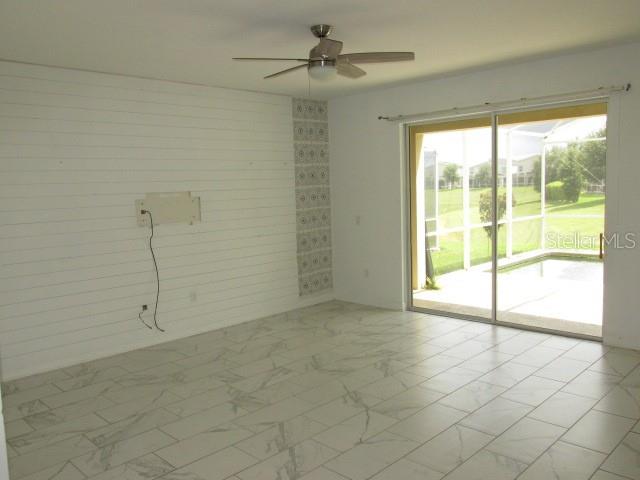 A living room with white shiplap walls, marble-look tile floors, and a sliding glass door — 8982 CABOT CLIFFS DRIVE, DAVENPORT, FL