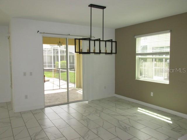 A dining area features a modern black chandelier, tile flooring, and a sliding glass door — 8982 CABOT CLIFFS DRIVE, DAVENPORT, FL