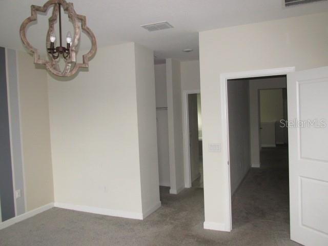 A room with gray carpeting, a decorative chandelier, and doorways leading to other interior spaces — 8982 CABOT CLIFFS DRIVE, DAVENPORT, FL