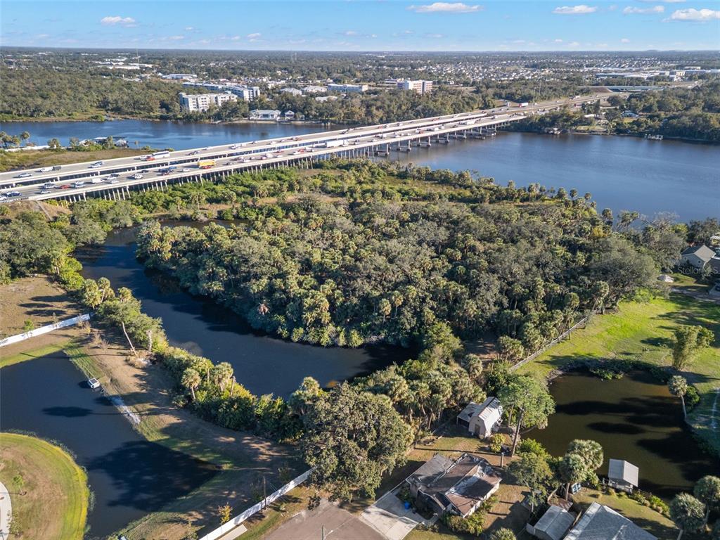 An aerial view shows a wooded lot, ponds, and a bridge crossing a river — 9511 RIVER COVE DRIVE, RIVERVIEW, FL