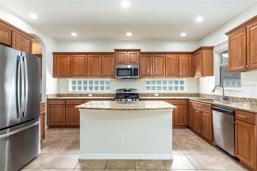 A kitchen with wood cabinets, granite countertops, a central island, and glass block windows — 13844 AMELIA POND DRIVE, WINDERMERE, FL