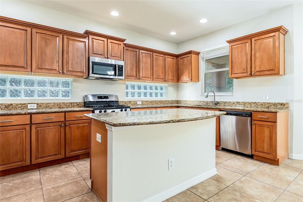 A kitchen with wood cabinets, granite countertops, a center island, and stainless steel appliances — 13844 AMELIA POND DRIVE, WINDERMERE, FL