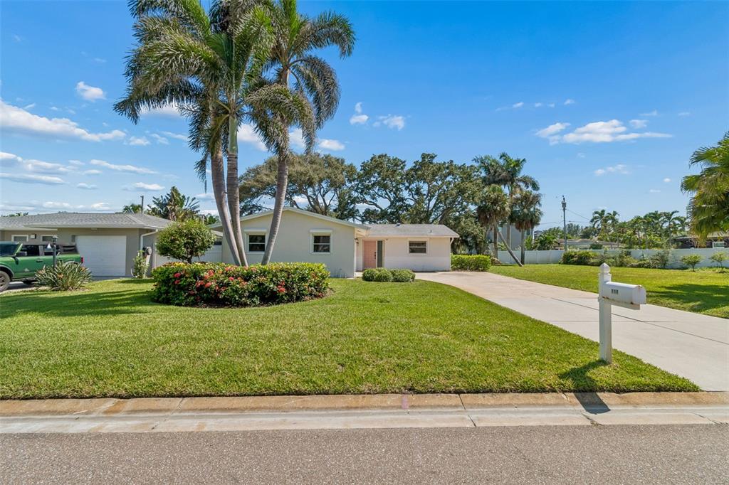 A single-story house with a palm tree, a green truck, and a concrete driveway — 114 8TH STREET, BELLEAIR BEACH, FL