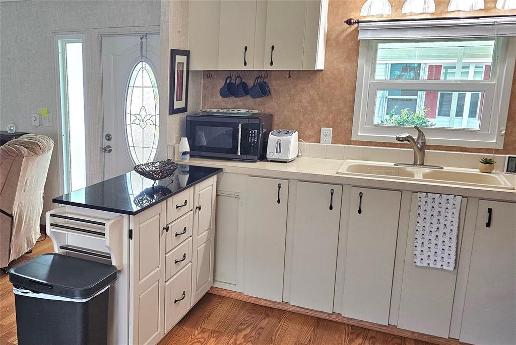 A kitchen features light-colored cabinets, a black countertop island, and a double-basin sink — 4906 E 7TH A STREET E UNIT 712, BRADENTON, FL