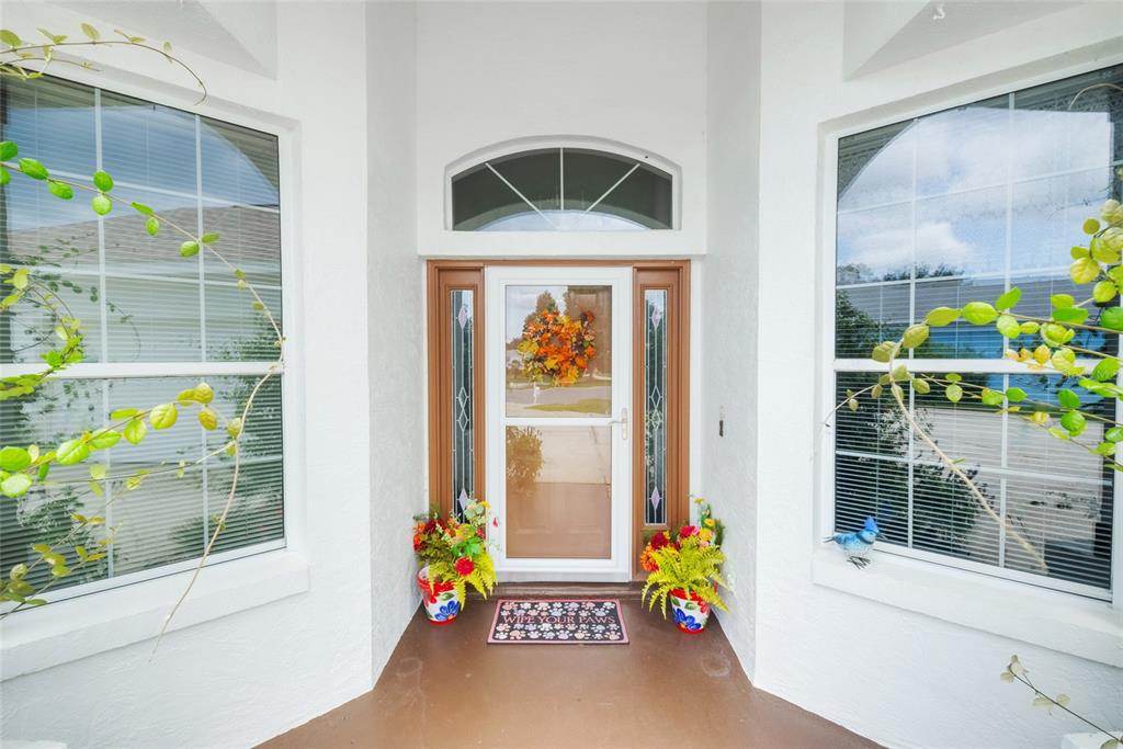 A front entryway features a white door with sidelights, a storm door, and two potted plants — 365 W BARCLAY COURT, BEVERLY HILLS, FL