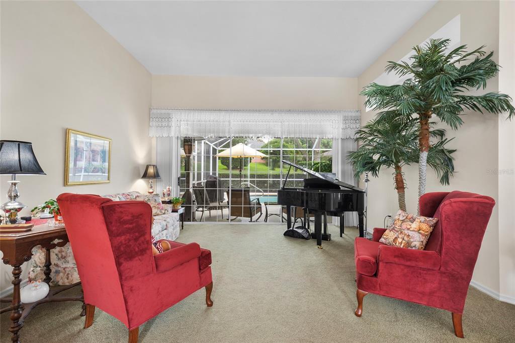 A living room features two red armchairs, a grand piano, and a sliding glass door — 365 W BARCLAY COURT, BEVERLY HILLS, FL