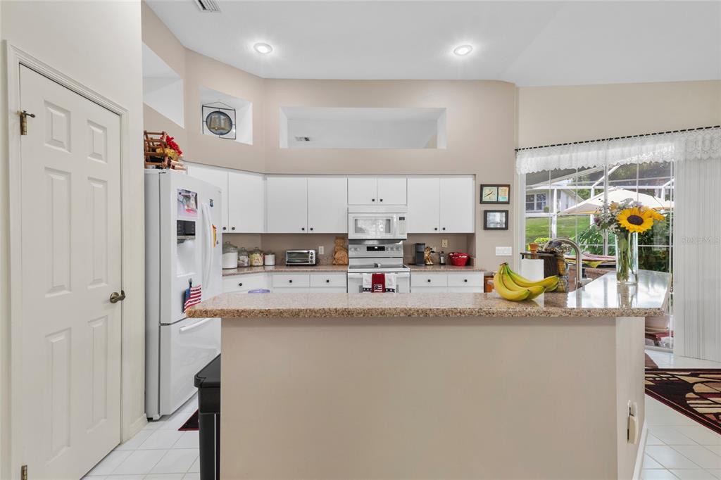 A kitchen with white cabinets, granite countertops, a breakfast bar, and a white refrigerator — 365 W BARCLAY COURT, BEVERLY HILLS, FL