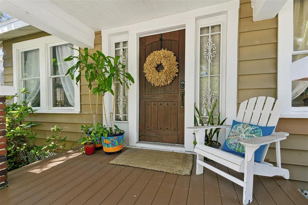A wooden front door with a wreath sits on a porch with a white chair — 2319 W NORTH B STREET, TAMPA, FL