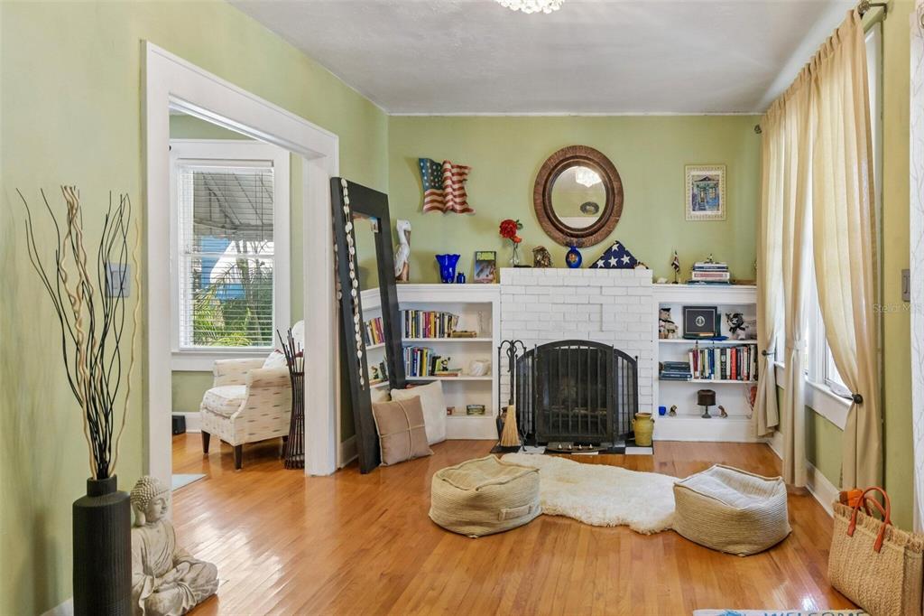 A living room with hardwood floors, a white brick fireplace, built-in shelves, and light green walls — 2319 W NORTH B STREET, TAMPA, FL