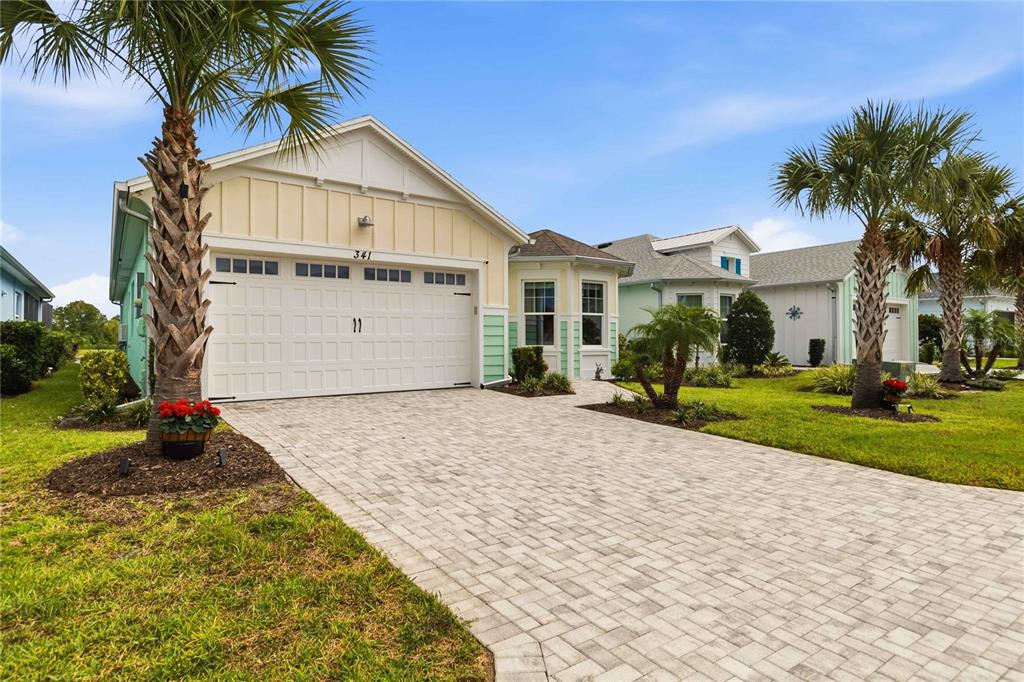 A single-story house with a paved driveway, light yellow siding, and a two-car garage — 341 COMPASS ROSE DRIVE, DAYTONA BEACH, FL