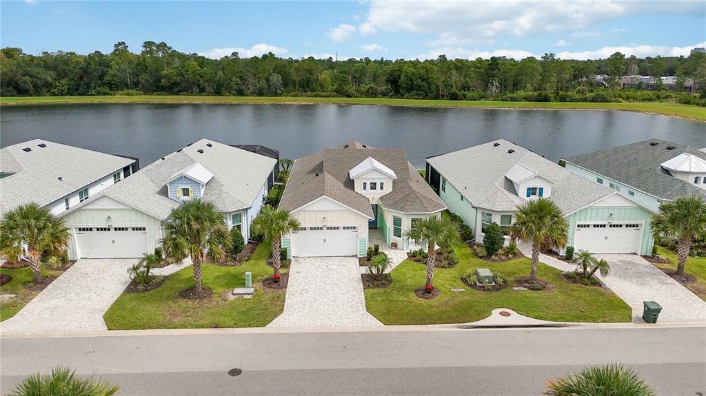 An aerial view shows four suburban houses with paved driveways facing a large lake — 341 COMPASS ROSE DRIVE, DAYTONA BEACH, FL