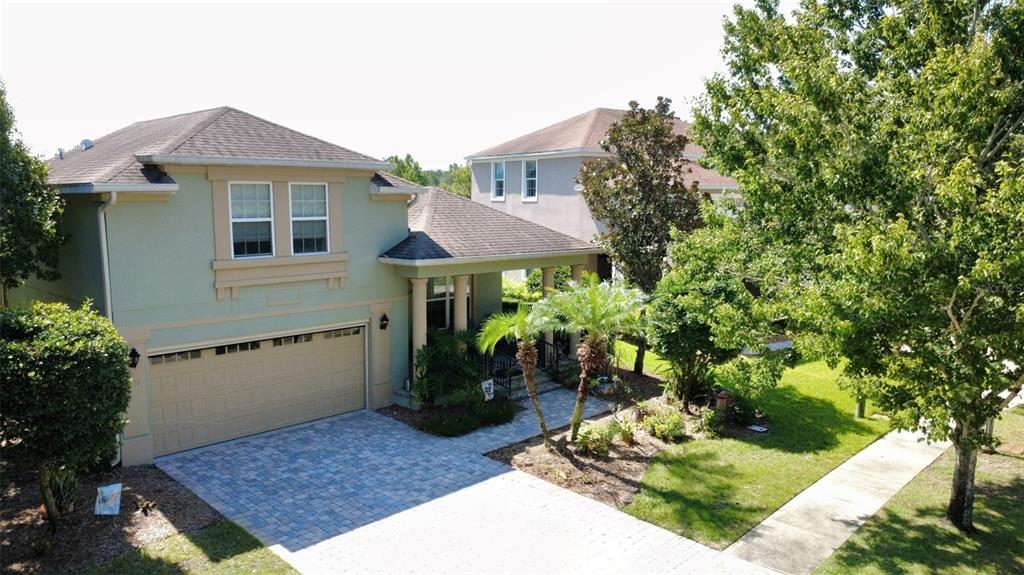 An aerial view shows a two-story light green house with a paved driveway and landscaping — 3214 NEEDLEGRASS LANE, HARMONY, FL