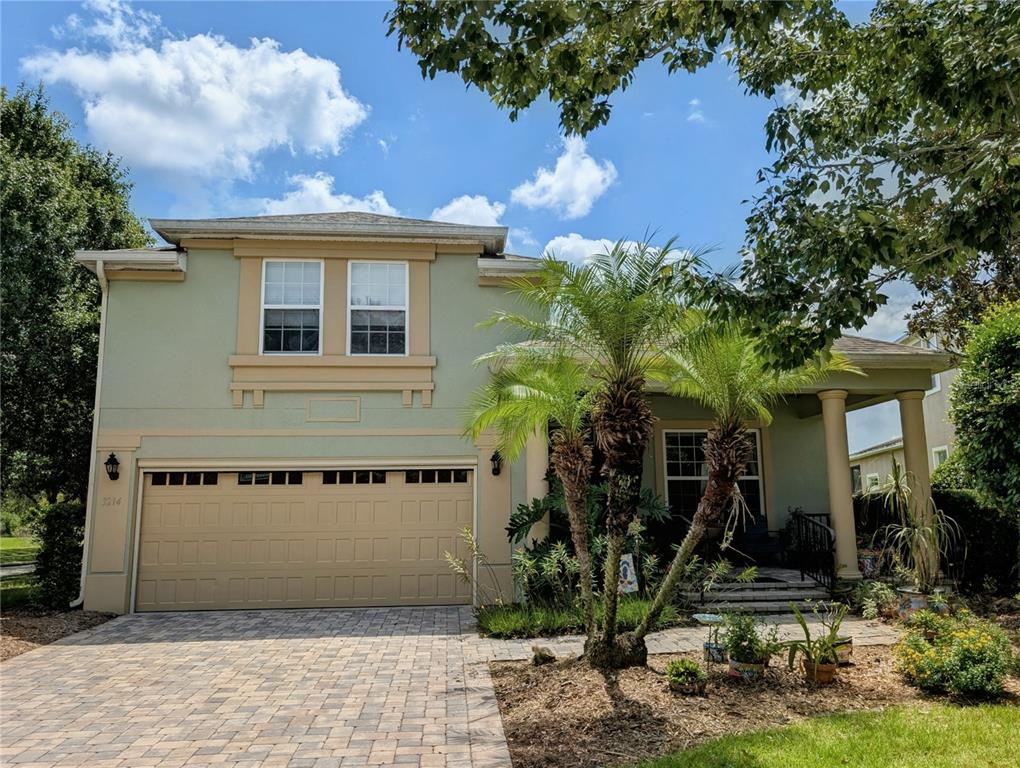 A two-story house with a green exterior, a tan garage door, and a front porch — 3214 NEEDLEGRASS LANE, HARMONY, FL