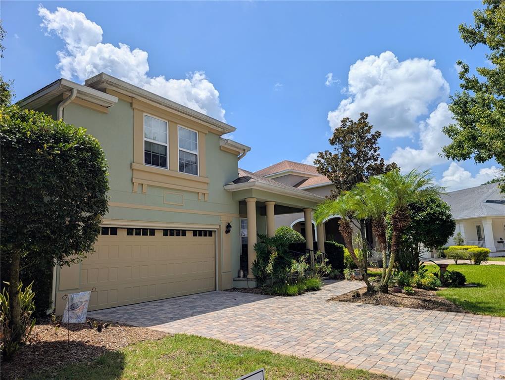 A two-story house with a light green exterior, tan garage door, and a paved driveway — 3214 NEEDLEGRASS LANE, HARMONY, FL