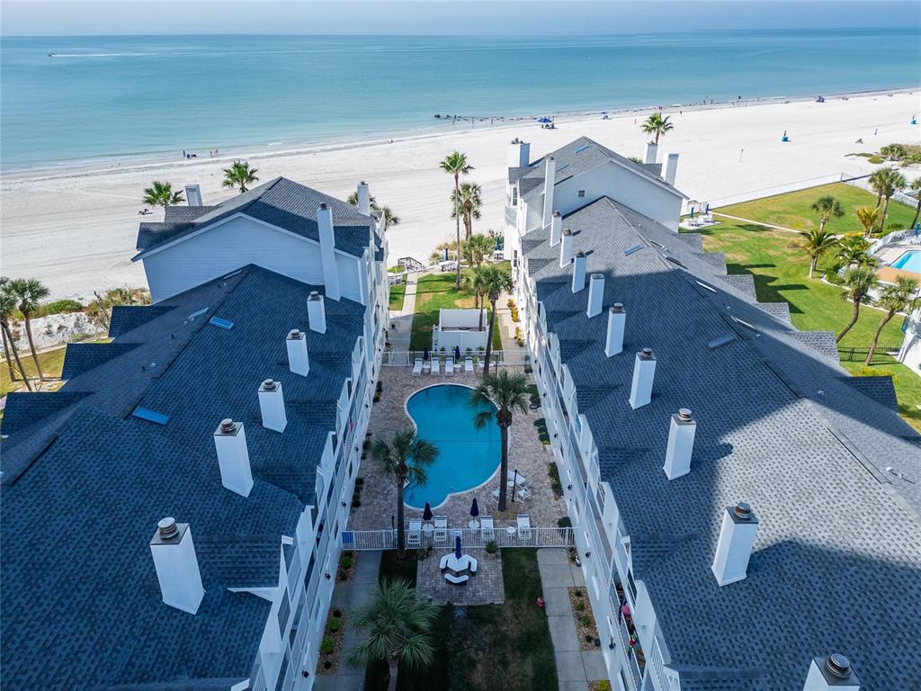An aerial view shows two white buildings flanking a swimming pool near a sandy beach — 17960 GULF BOULEVARD UNIT 119, REDINGTON SHORES, FL
