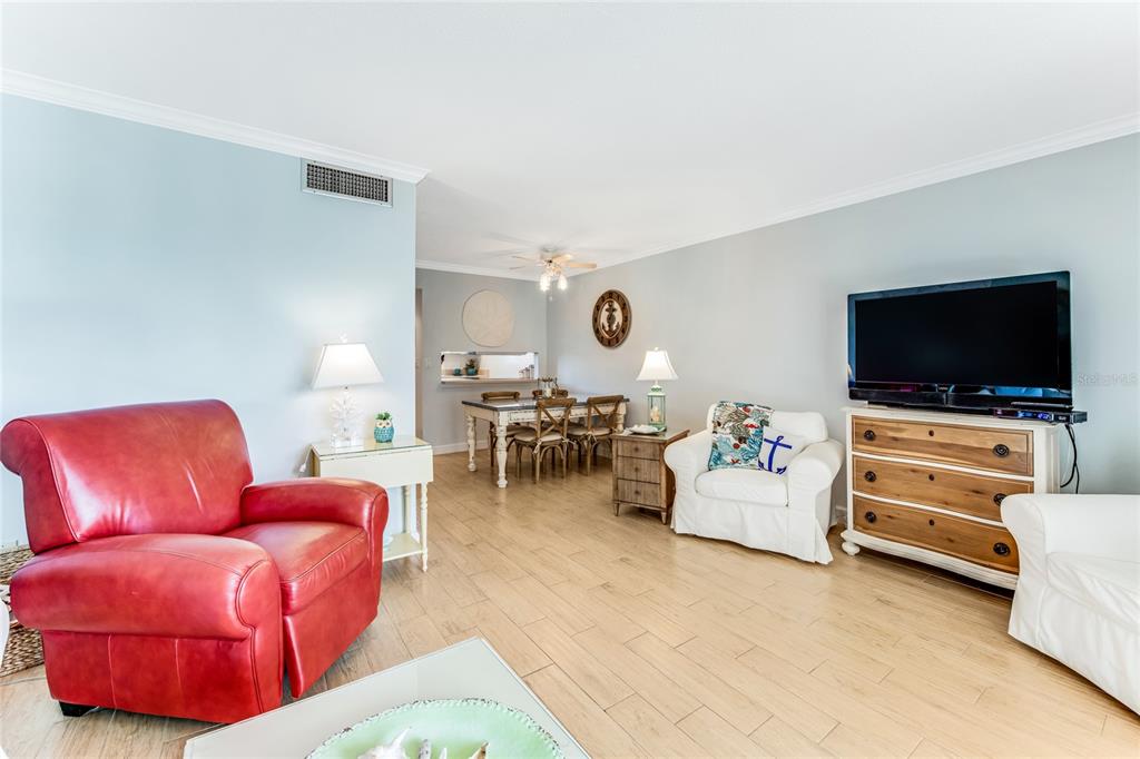 A living room with a red leather chair, white armchairs, and a dining area beyond — 935 OCEAN SHORE BOULEVARD UNIT 303, ORMOND BEACH, FL