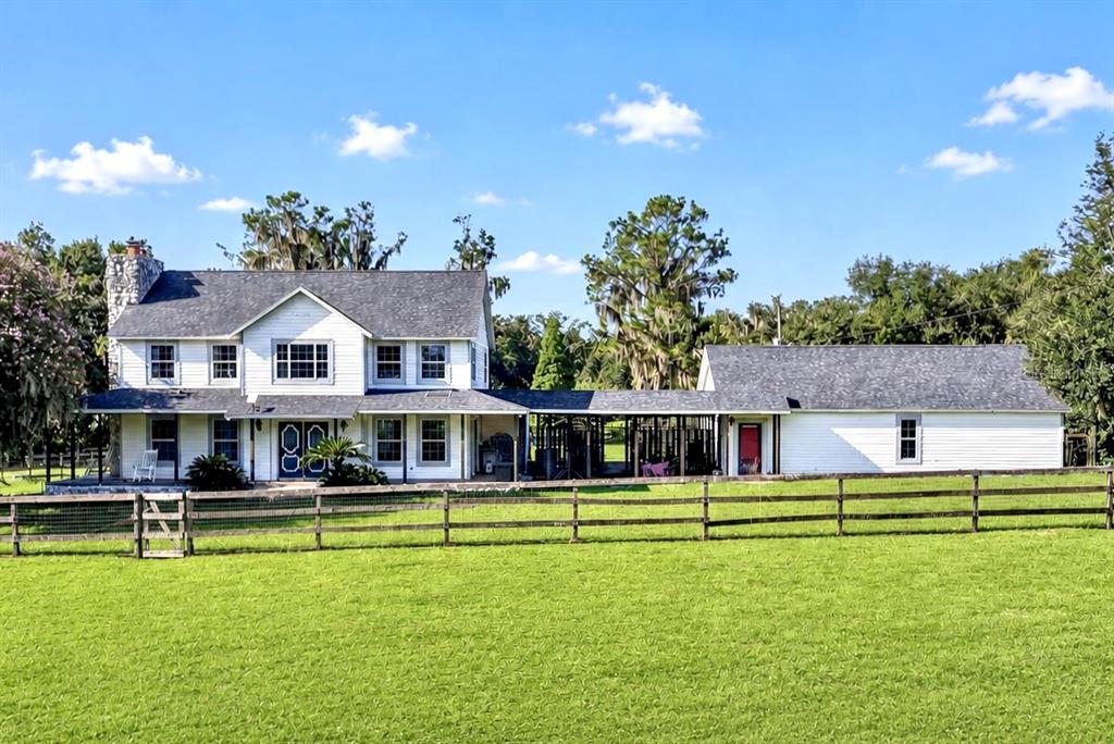 A two-story white farmhouse with a stone chimney and a long covered breezeway — 8922 PRITCHER ROAD, LITHIA, FL