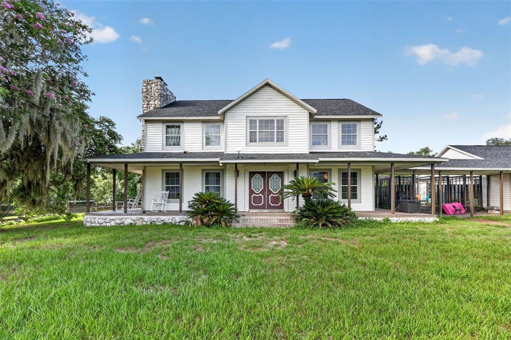 A two-story white house with a wrap-around porch and a stone chimney — 8922 PRITCHER ROAD, LITHIA, FL