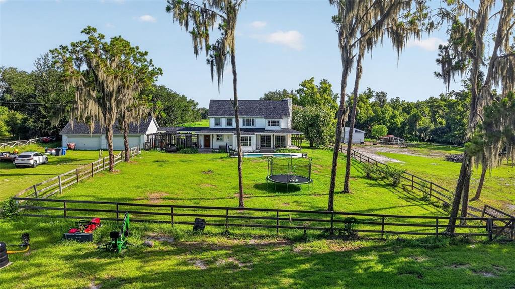 A two-story house with a pool, detached garage, and fenced yard sits on a grassy lot — 8922 PRITCHER ROAD, LITHIA, FL