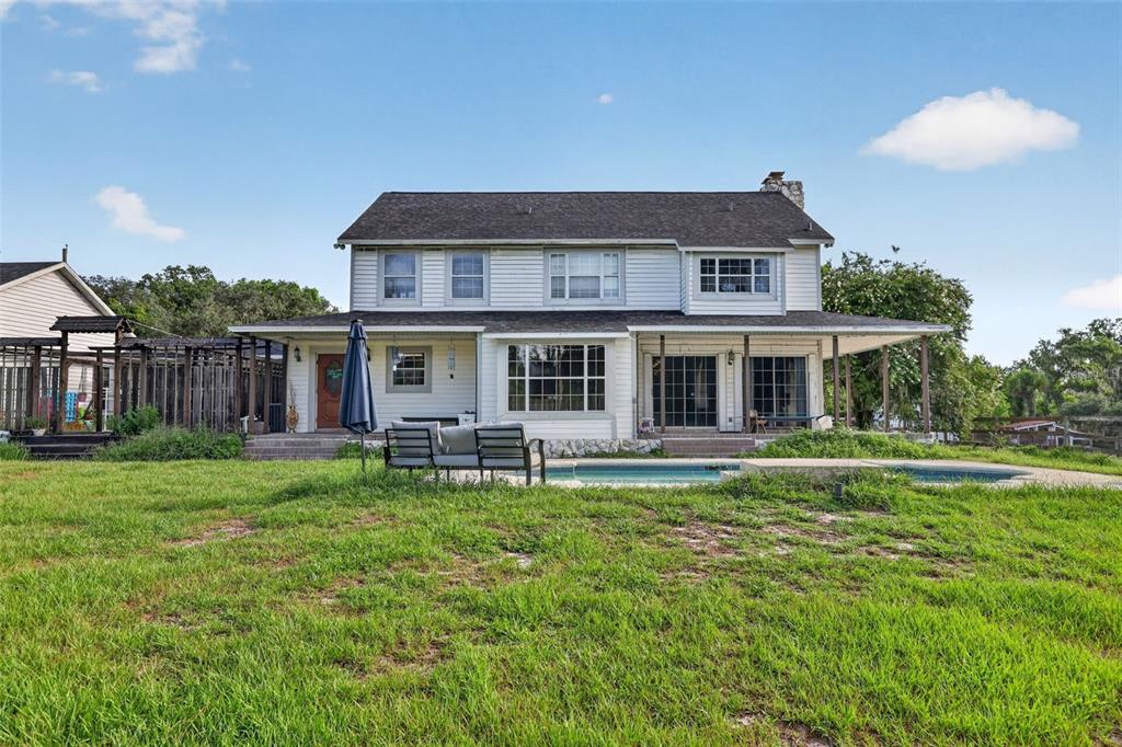 The exterior of a two-story white house features a swimming pool and a covered porch — 8922 PRITCHER ROAD, LITHIA, FL