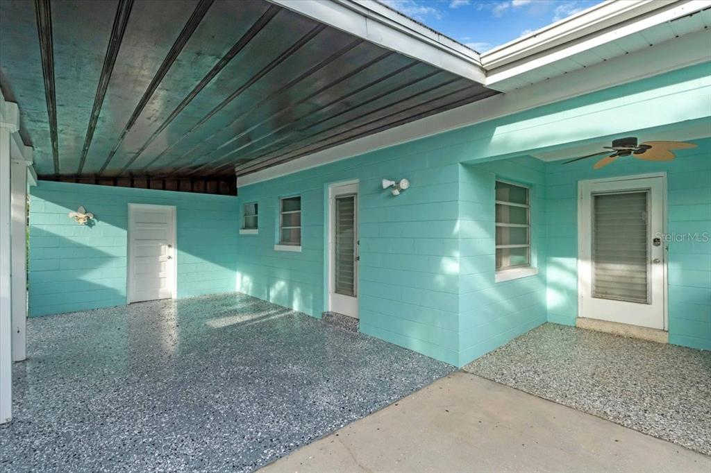 A covered patio with light blue concrete block walls and a speckled epoxy floor — 11435 2ND STREET E, TREASURE ISLAND, FL