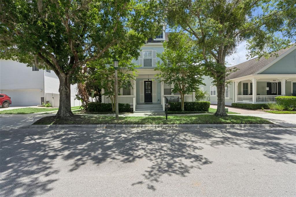 A light blue two-story house with a front porch sits behind two large trees — 930 CROTON ROAD, CELEBRATION, FL
