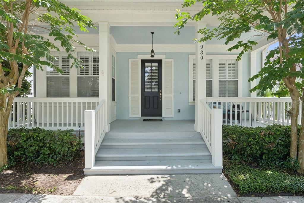 A light blue house exterior features a front porch with white railings and stairs — 930 CROTON ROAD, CELEBRATION, FL
