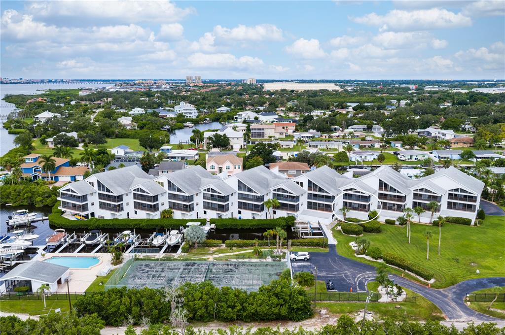 An aerial view shows a row of waterfront townhouses with boat slips and a tennis court — 515 LEFFINGWELL AVENUE UNIT 112, ELLENTON, FL