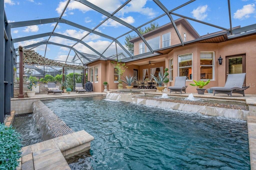A screened-in patio features a swimming pool with water features and lounge chairs — 16012 TERNGLADE DRIVE, LITHIA, FL