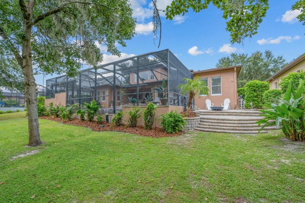 A tan house features a large screened-in pool enclosure and a stone patio with steps — 16012 TERNGLADE DRIVE, LITHIA, FL