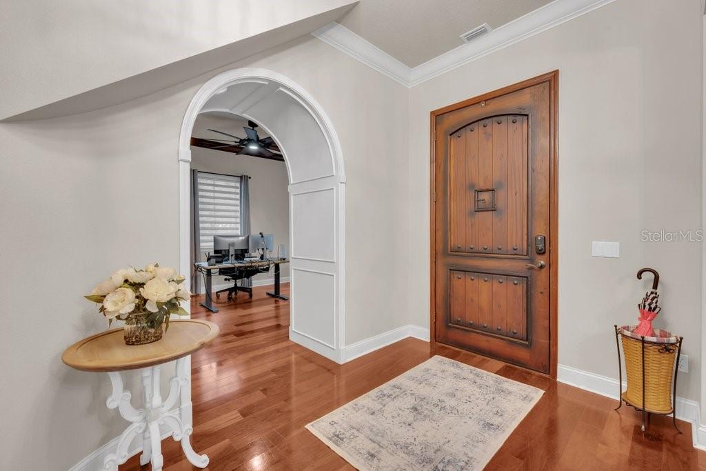 An entryway with hardwood floors, a wooden front door, and an arched doorway to an office — 16012 TERNGLADE DRIVE, LITHIA, FL