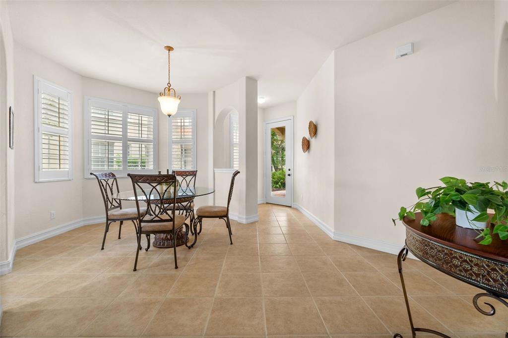 A dining area with tile floors, a glass-top table, and a glass-paneled exterior door — 5626 CAPE HARBOUR DRIVE UNIT 102, CAPE CORAL, FL