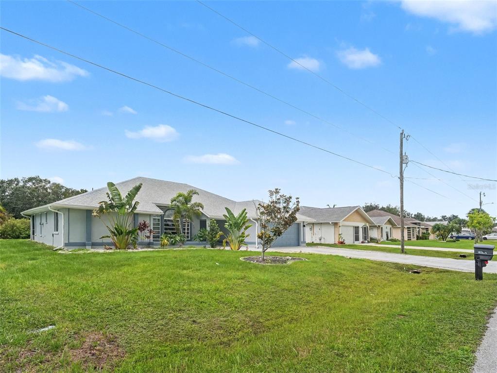 A single-story house with a gray roof and light-colored siding sits on a grassy lot — 25892 AYSEN DRIVE, PUNTA GORDA, FL