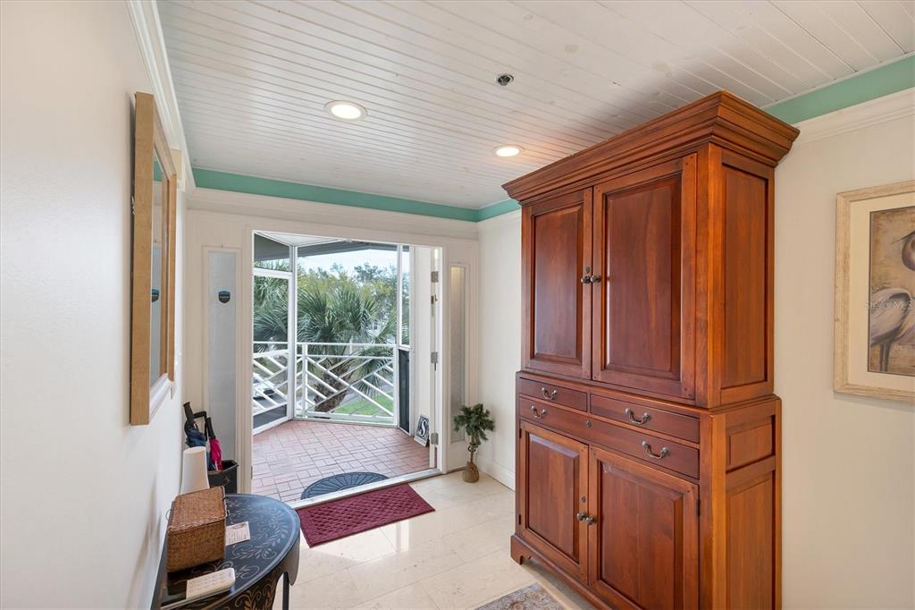 An entryway with a large wooden armoire, tile floors, and a door leading to a balcony — 11000 PLACIDA ROAD UNIT 2103, PLACIDA, FL
