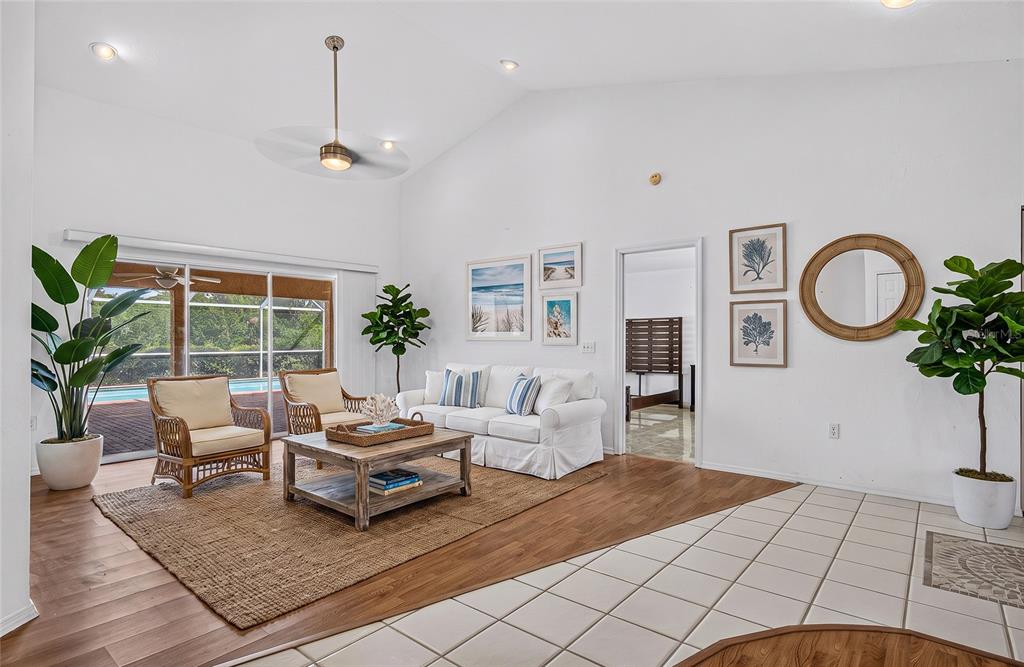 A living room features white walls, a vaulted ceiling, wood flooring, and a sliding glass door — 105 JACARANDA BOULEVARD, VENICE, FL